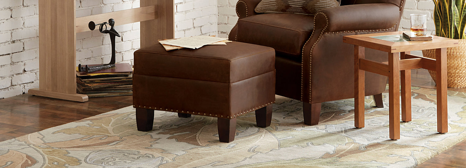 Stickley brown chair and ottoman setup featuring designer rug with large leaf print