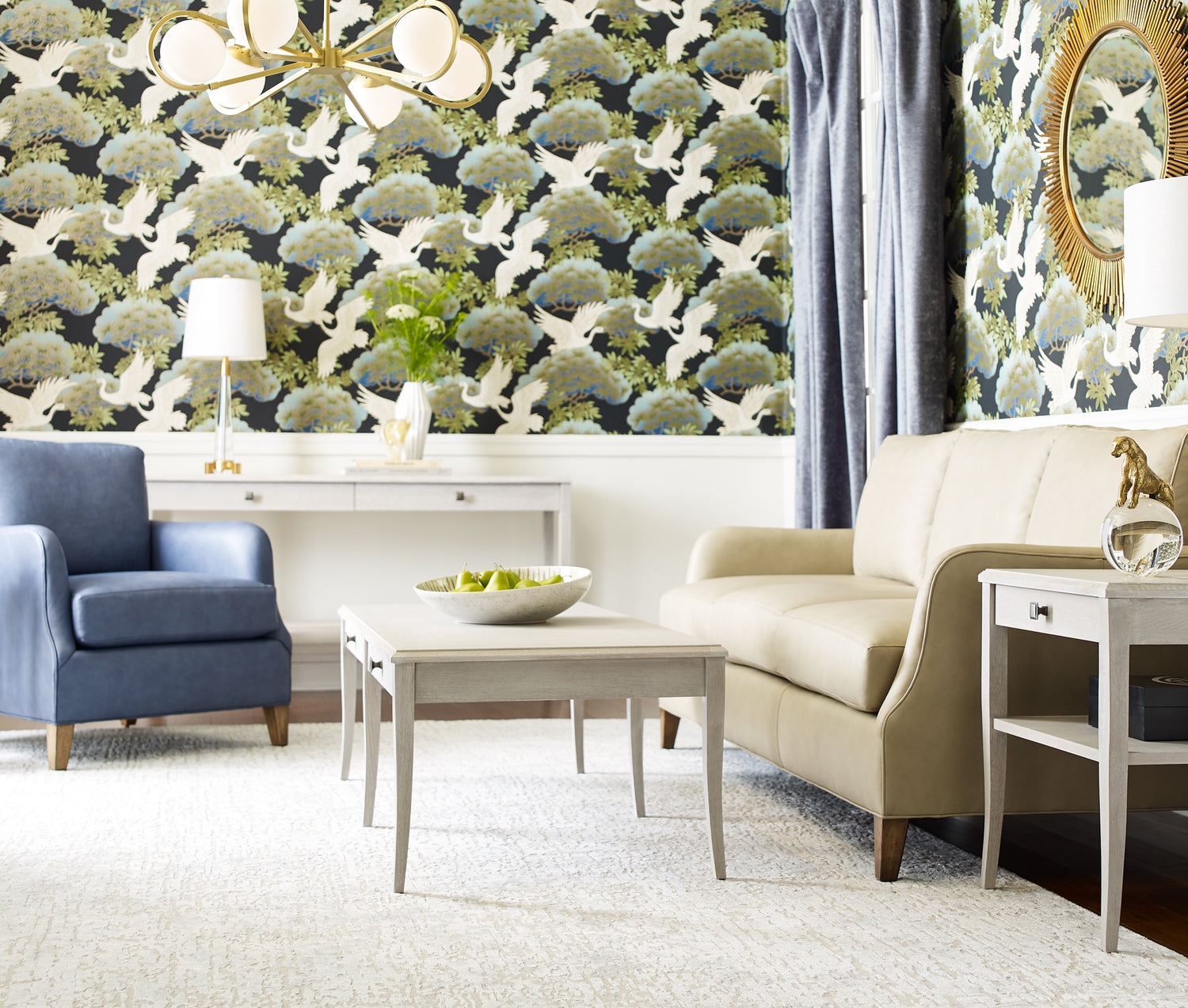 Origins by Stickley upholstery Harper living room setup showcasing a side view of a tan sofa, a blue leather chair, and a white coffee table against a room lined with decorative green and blue wallpaper.