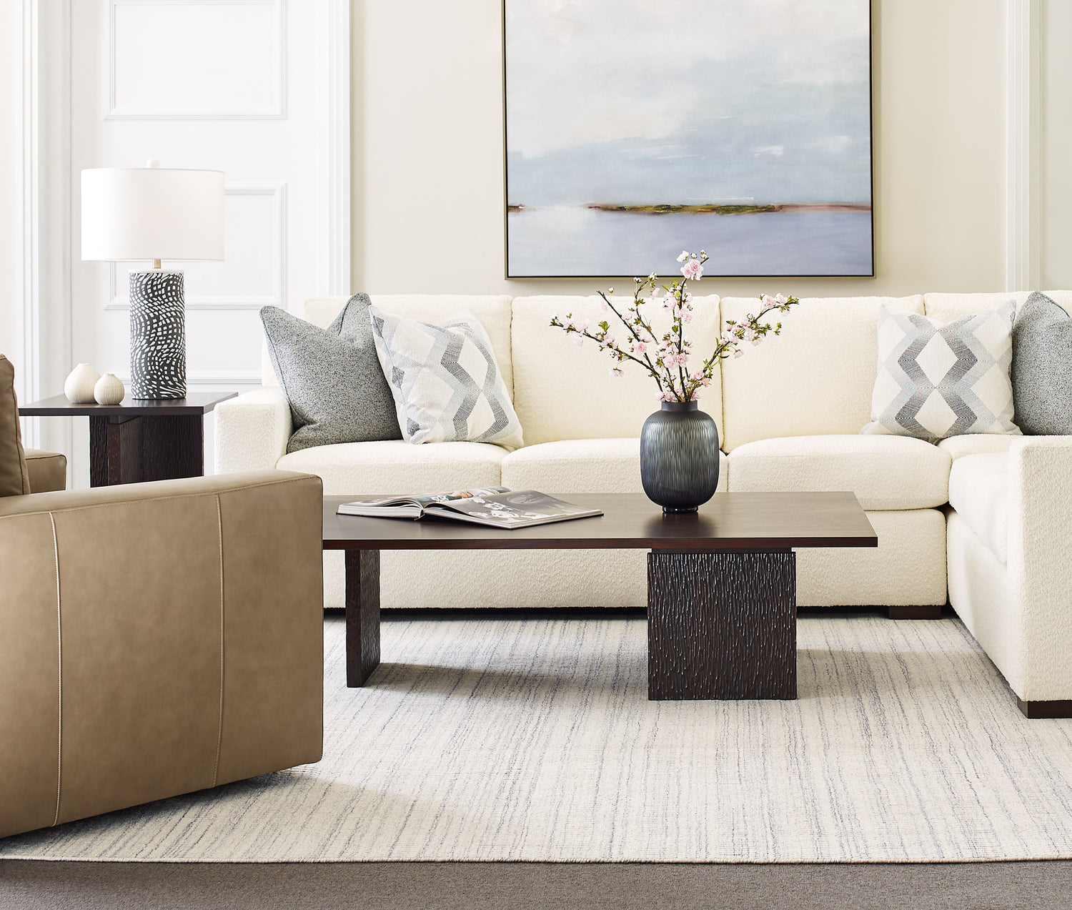 Origins by Stickley Keene white sectional with gray and white accent pillows and a dark brown coffee table in front.