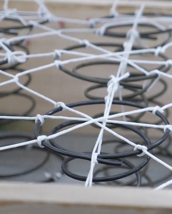 A close up of steel springs tied together with white elastic bands.