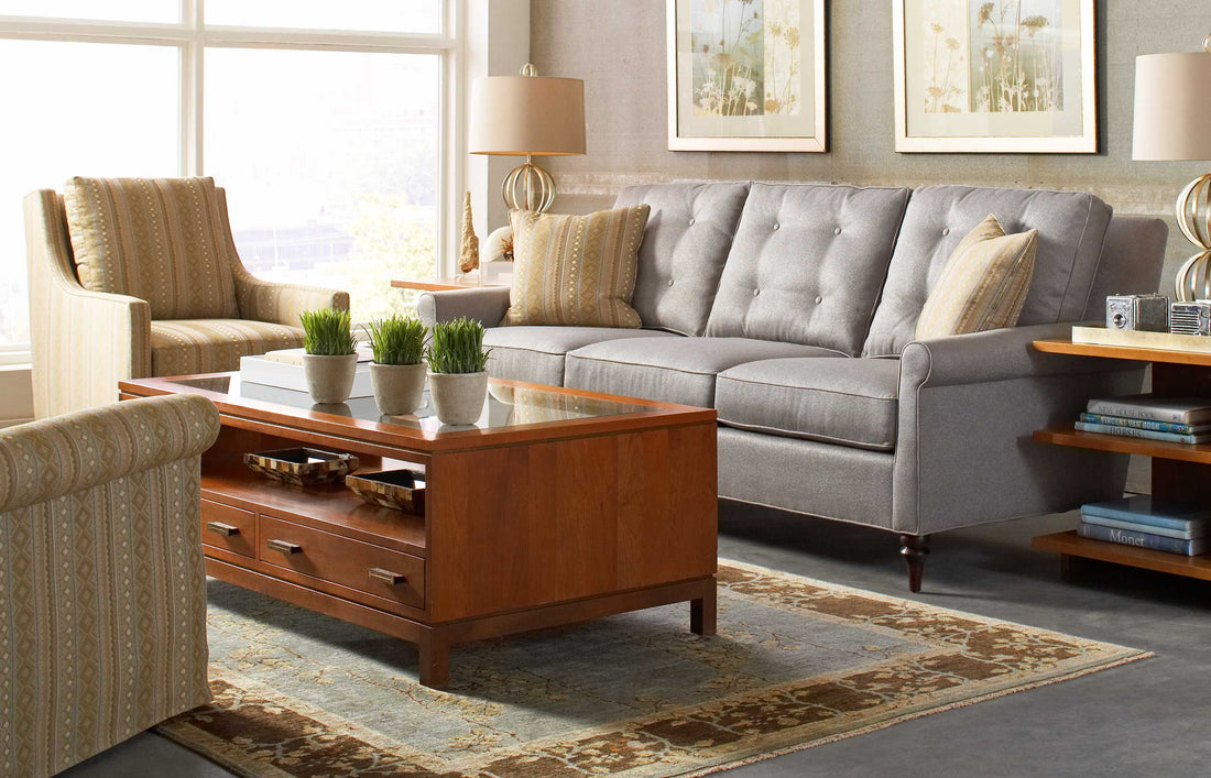 Lifestyle of a light gray fabric 500 Series Three-Cushion Sofa with two yellow decorative pillows against each arm, there is a wood coffee table in front and two yellow accent chairs also surrounding the table