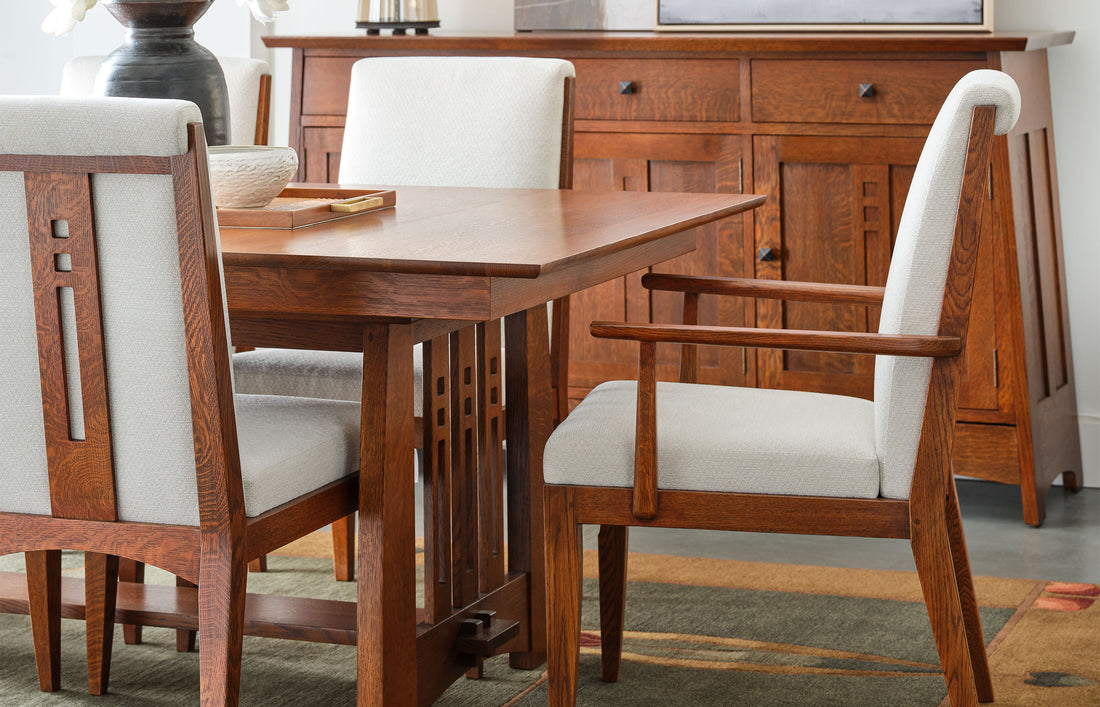 Stickley Highlands Skye Upholstered Chairs in white fabric with Mission-style oak frames, surrounding a matching oak dining table with decorative inlays, set in a dining room with a coordinating sideboard and earthy-toned rug.