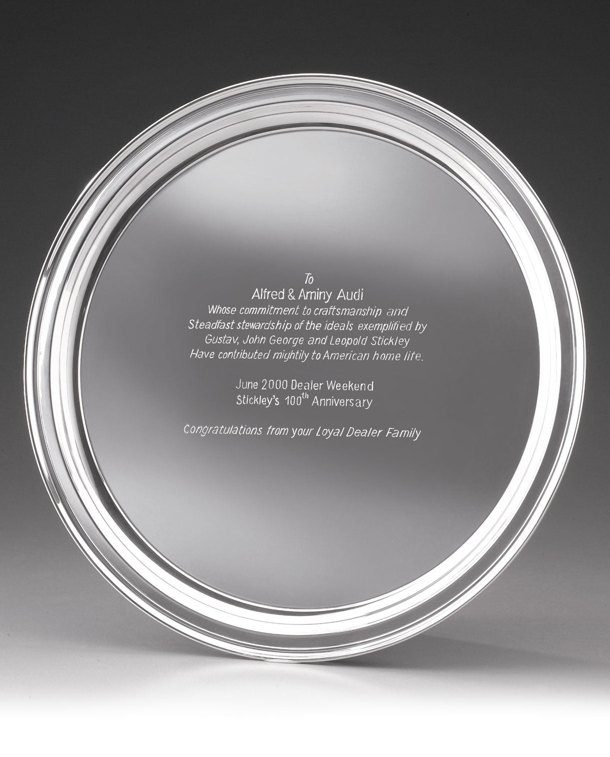 Clear glass award plate engraved with a dedication to Alfred and Aminy Audi, honoring their commitment to craftsmanship and upholding the ideals of Gustav, John George, and Leopold Stickley. The award was presented during the June 2000 Dealer Weekend celebrating Stickley’s 100th Anniversary, with congratulations from their Loyal Dealer Family.