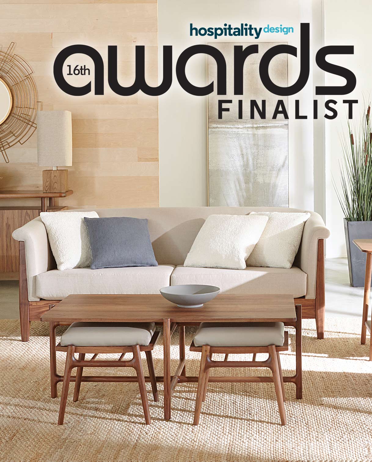Modern living room furniture set featuring a cream-colored sofa with wood framing, two small wood and upholstered stools, and a wooden coffee table topped with a minimalist gray bowl. The space is styled with neutral tones and natural textures. The image is labeled “16th Hospitality Design Awards Finalist.”
