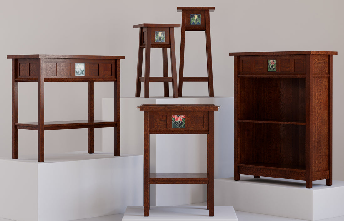 Stickley’s 125th Anniversary Collector's Series featuring five handcrafted Mission-style pieces in rich oak finishes, each accented with an exclusive decorative art tile inspired by early 20th-century designs. The group includes stools, side tables, and a bookcase, showcased on white platforms against a neutral background for a museum-like presentation.