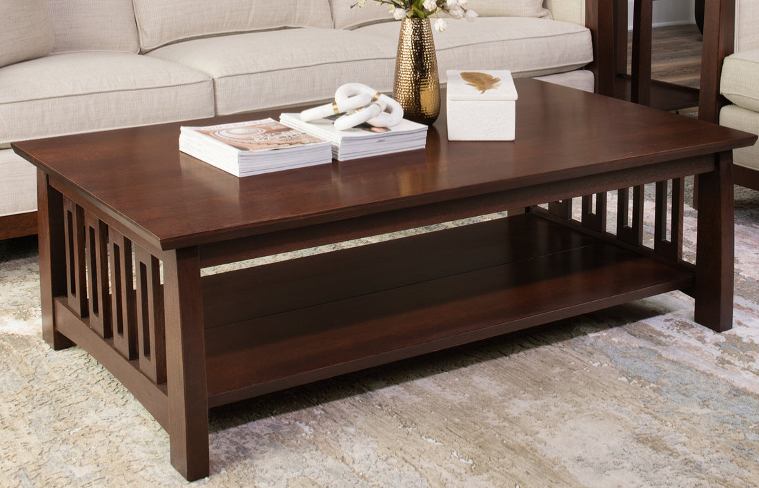 Stickley Highlands cocktail table in a rich dark oak finish, featuring Mission-style slatted sides, a lower storage shelf, and a rectangular top styled with books and decorative accents, set in a neutral-toned living room.