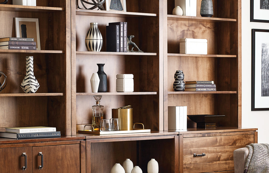 Close-up of the Origins by Stickley home office bookcase and file cabinet in a warm wood finish, styled with modern black-and-white ceramics, stacked books, and decorative accessories. The clean lines and rich wood grain bring a contemporary warmth to the space, blending form and function for stylish home organization.