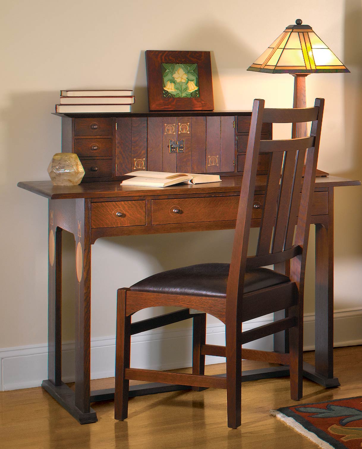 Lifestyle of a Harvey Ellis desk, a Harvey Ellis Deck, books, and a stained glass lamp resting on top