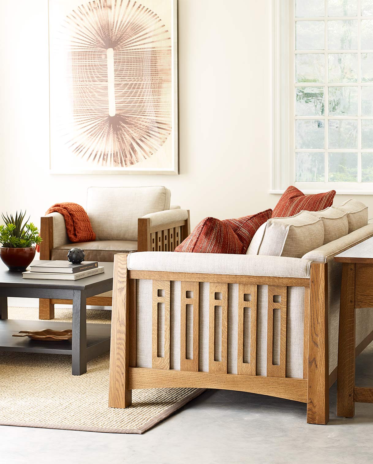 A Stickley Highlands collection living room setup with a sofa and accent chair in front of a cream wall and cream and pink artwork