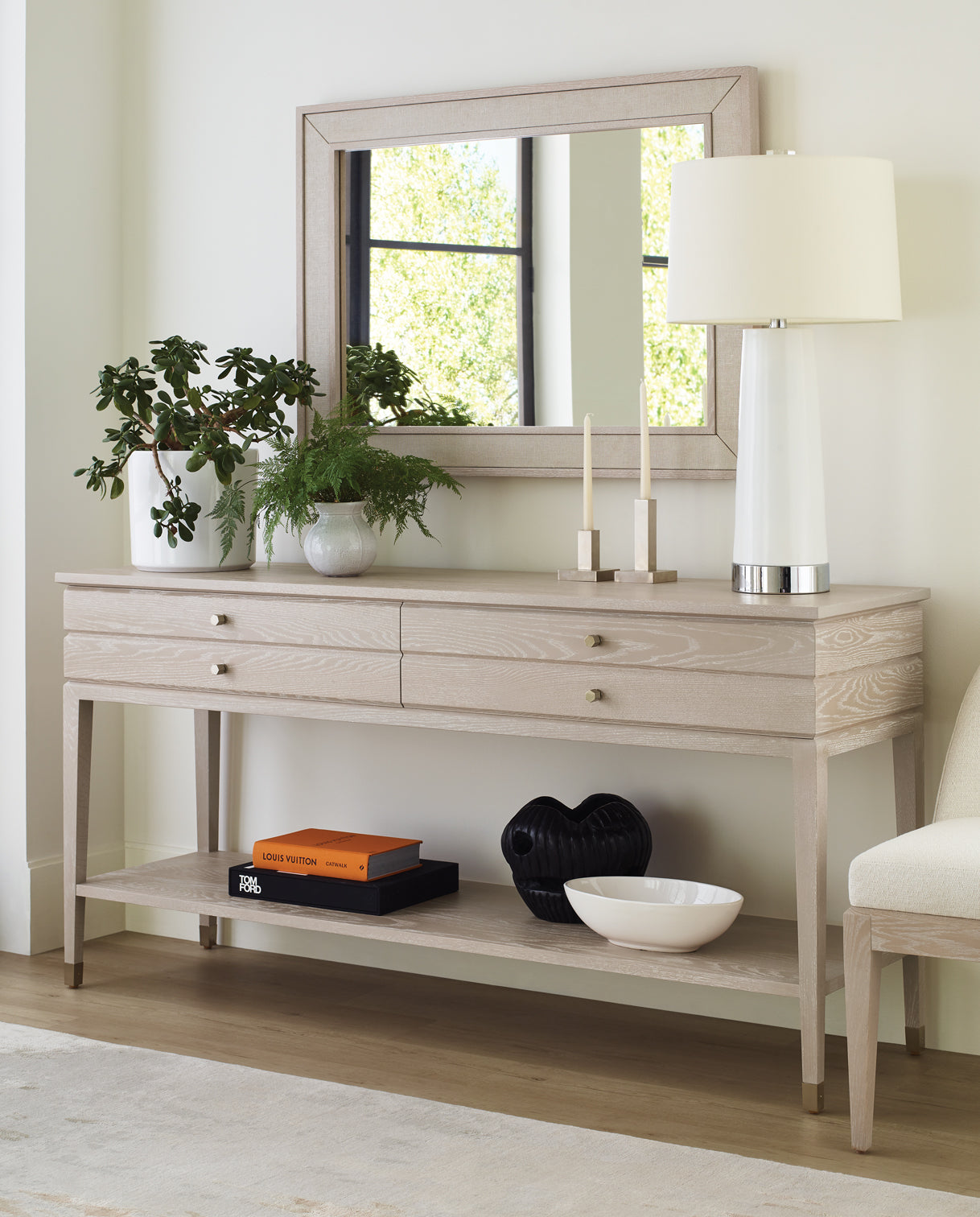Stickley Maidstone Two-Drawer Server in a soft whitewashed finish, shown in a dining room setting with brass hardware, lower open shelf, and styled with greenery, modern tabletop decor, and a coordinating mirror above.