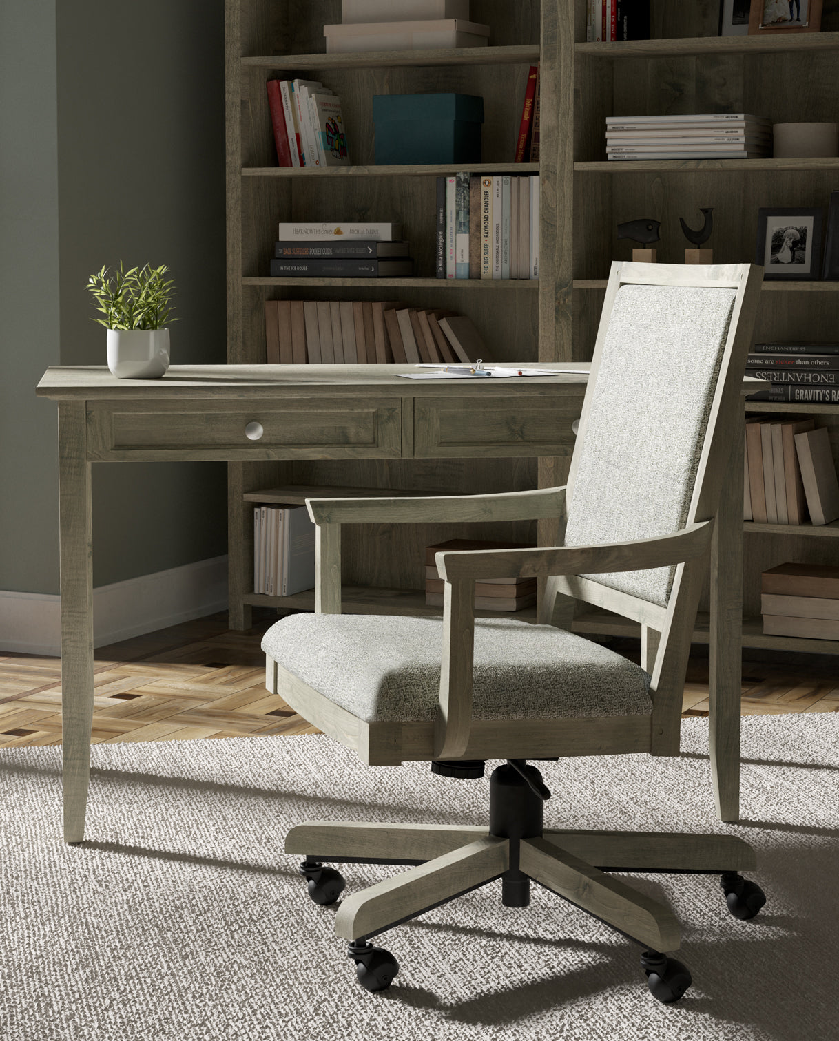 Lifestyle of a Revere Desk that has a small potted plant on top, there is an Origins Swivel-Tilt Arm Chair pulled out from it