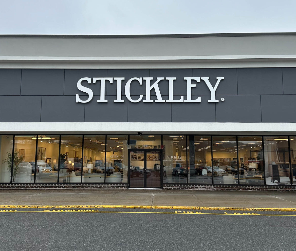 Exterior view of the Stickley showroom in White Plains, New York, featuring a sleek modern facade with large windows and bold signage—offering a welcoming entrance to a luxury furniture and design destination.