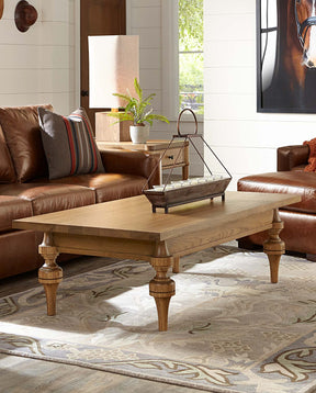 Lifestyle of the St. Lawrence Turned Cocktail Table in front of a brown leather couch and chair